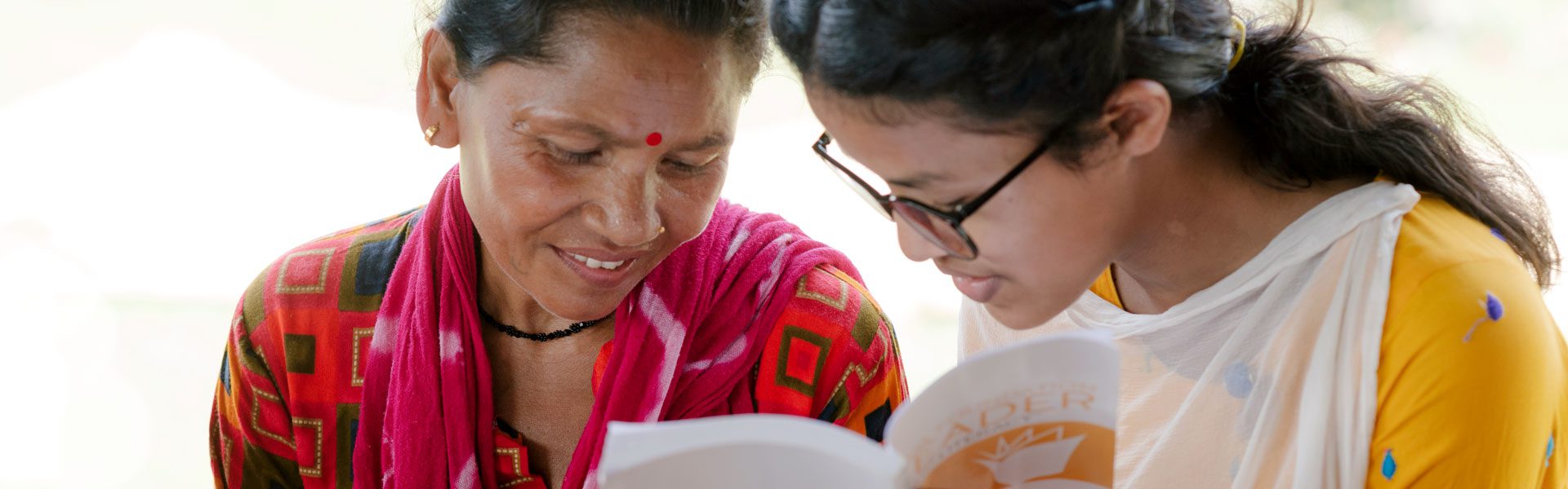 Zwei nepalesische Frauen schauen gemeinsam in ein Buch.