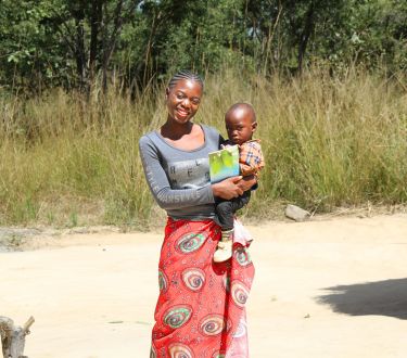 Mary mit einem Baby auf dem Arm in ihrem Dorf.