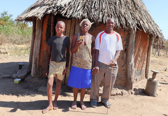 Nchena aus Simbabwe mit seiner Familie und seiner Audio-Bibel vor seiner Hütte.