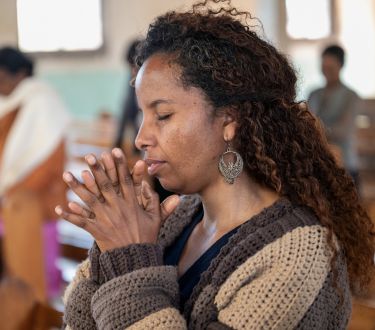 Eine Frau betet und hat die Hände zum Gebet gefaltet